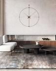 Modern living room with a white sofa, round black coffee table, and decorative wall clock.