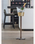 Clear ice bucket with gold base on a stand in a bar setting