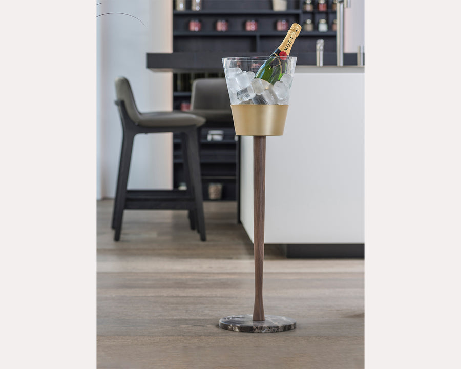 Clear ice bucket with gold base on a stand in a bar setting