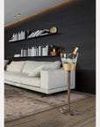 Modern living room with a white sofa, decorative shelves, and a gold ice bucket with a bottle.