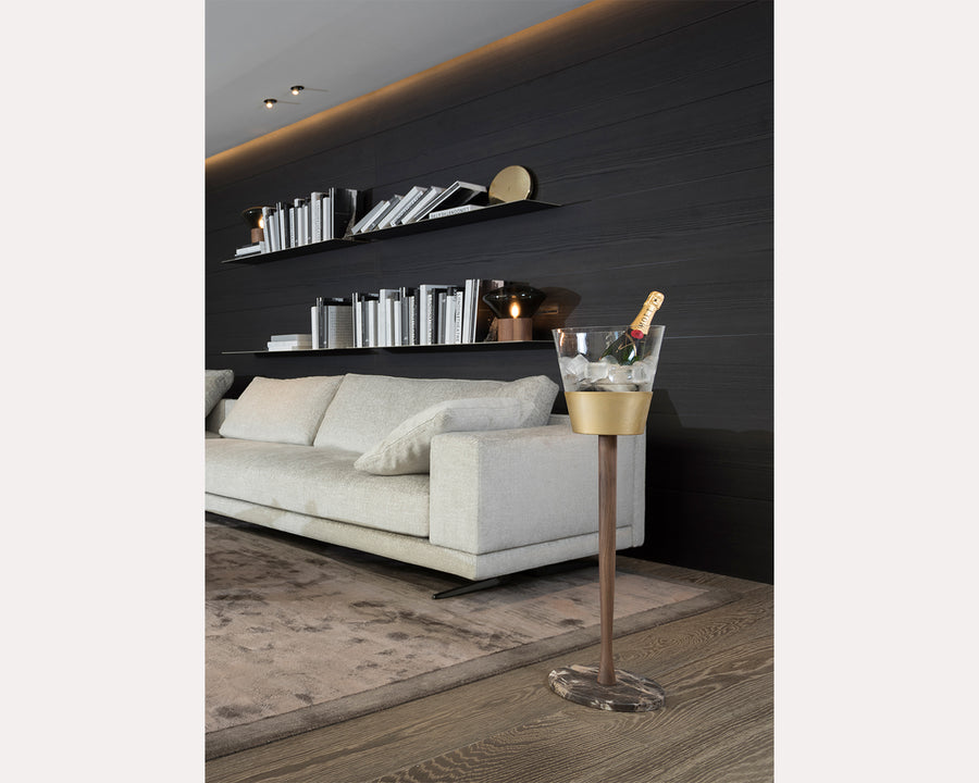 Modern living room with a white sofa, decorative shelves, and a gold ice bucket with a bottle.