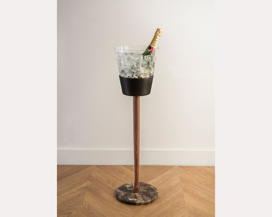 Decorative vase with a bottle on a stand against a white wall