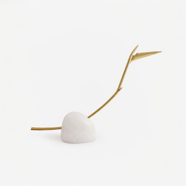 Decorative bird of paradise flower stem with a gold branch and white sphere on a light beige background