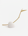 Decorative bird of paradise flower stem with a gold branch and white sphere on a light beige background