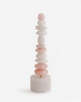 A table top totem sculpture made of stacked mixed colour quartz  on a white background