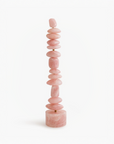A table top pink quartz totem sculpture on a white background