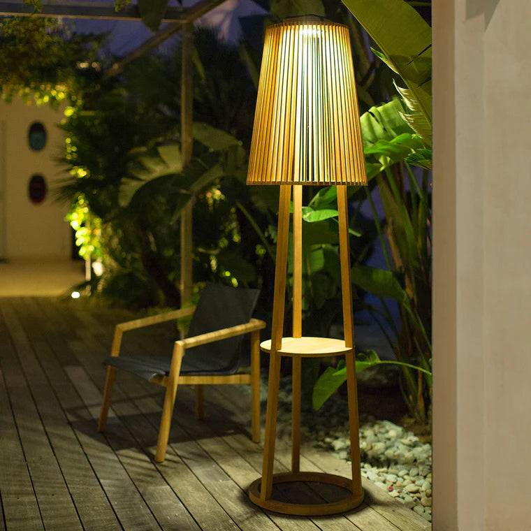 Wooden solar floor lamp and side table with pleated shade on a wooden deck at night  by Les Jardins available at Spacio retail stores in Mumbai & Kolkata. 