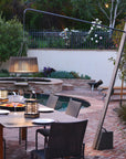 Outdoor patio setting with a dining table, chairs, and a pool in the background and a solar floor lamp by Les Jardins available at Spacio retail stores in Mumbia & Kolkata. 