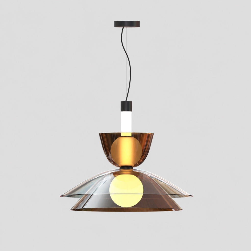 A modern pendant light fixture with a brushed bronze metal shade, a clear glass bowl, and a glowing warm yellow bulb inside, suspended by a black cord against a light gray background.