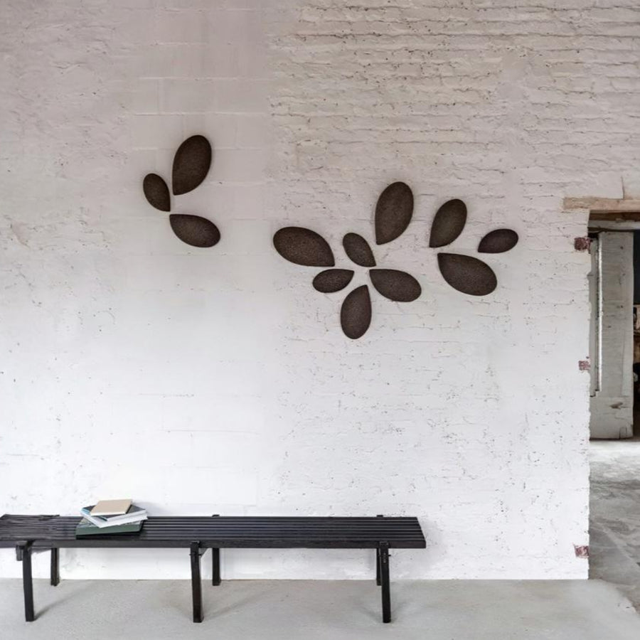 Decorative wall art on a white brick wall with a bench in the foreground.