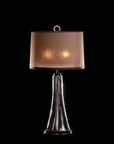 Table lamp with a brown lampshade and clear cylindrical base on a black background from Pieter Adam available at Spacio in India. 