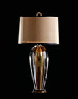 Decorative table lamp with a gold base and beige shade on a black background