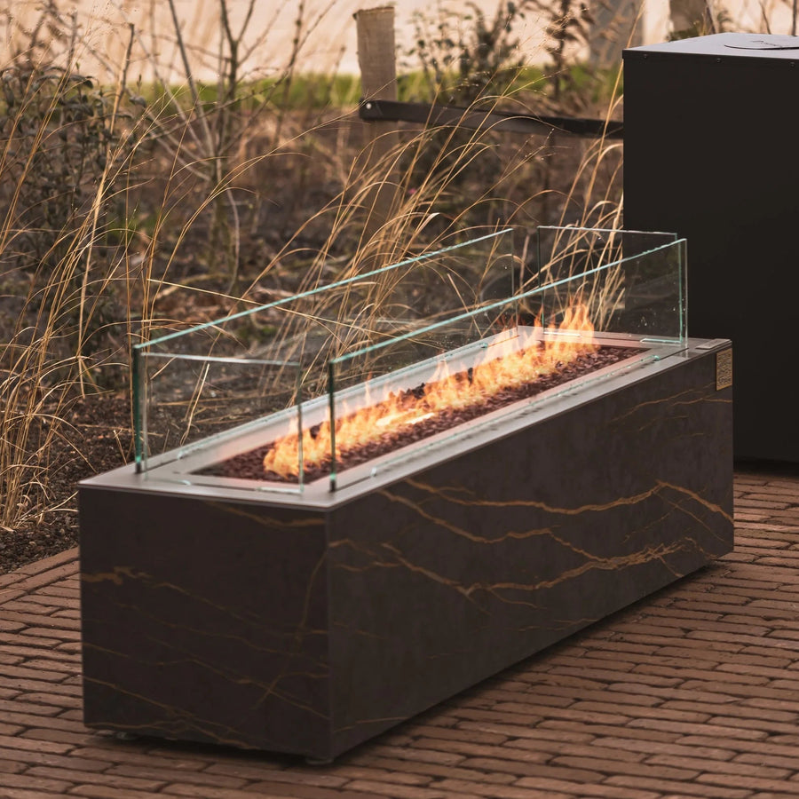 Outdoor gas fire place with flames on a brick patio from Planika available at Spacio retail stores in Mumbai & Kolkata. 