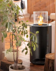 A black column fireplace in an indoor and outdoor setting. 