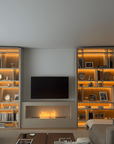 Modern living room with a fireplace, bookshelves, and a television.