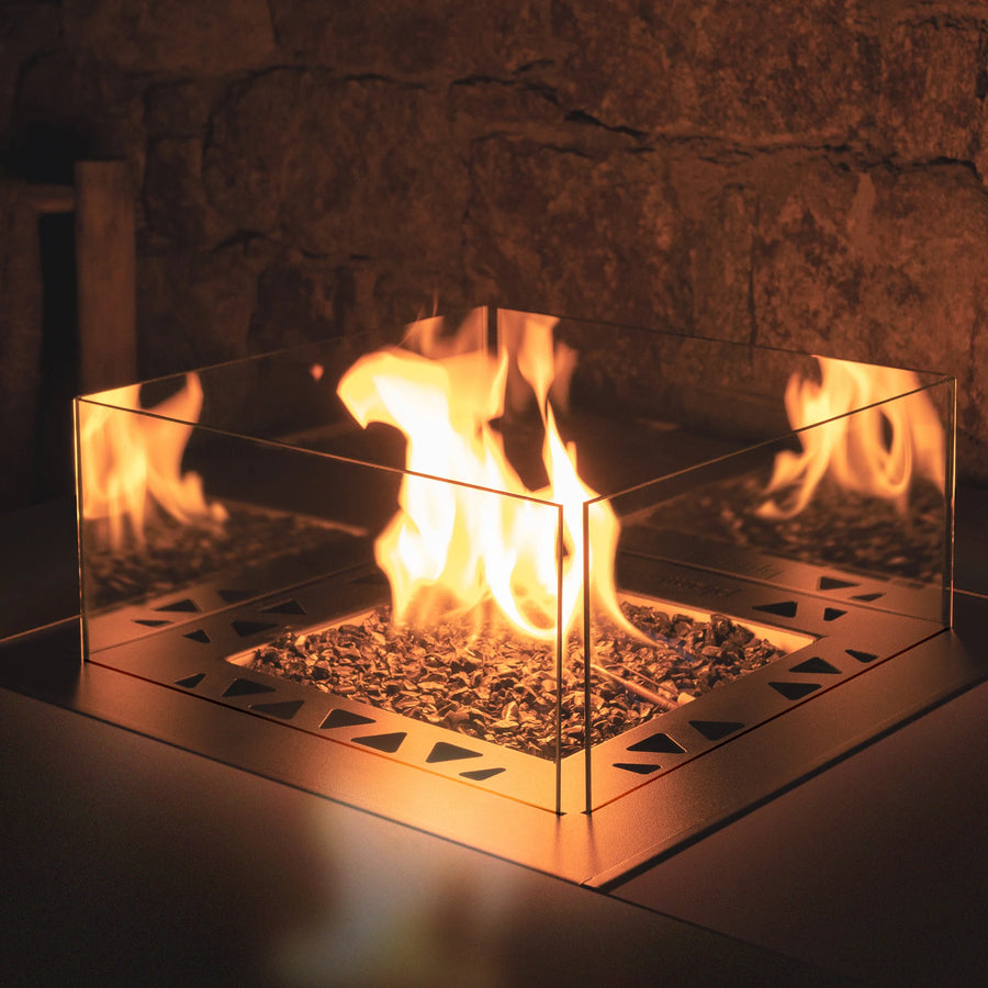 Glass fireplace insert with flames burning inside a stone fireplace.