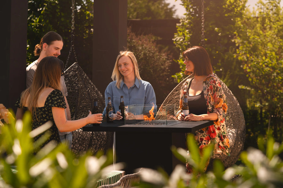 People sitting around a gas fireplace table with drinks in an outdoor setting 