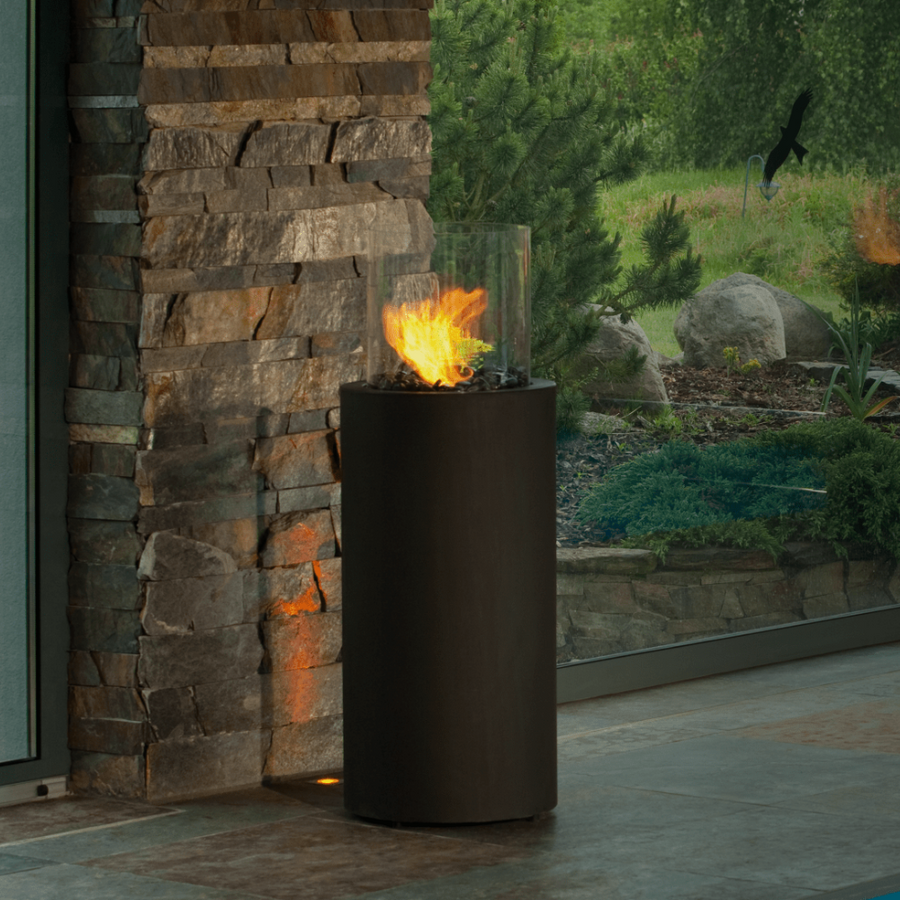 Portable indoor outdoor black column bioethanol fireplace from Planika in front of a brick stone column