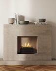 A free standing fireplace with artificial logs from Planika in a modern cement finish fireplace mantle along with some decor accessories styled on the mantle. 