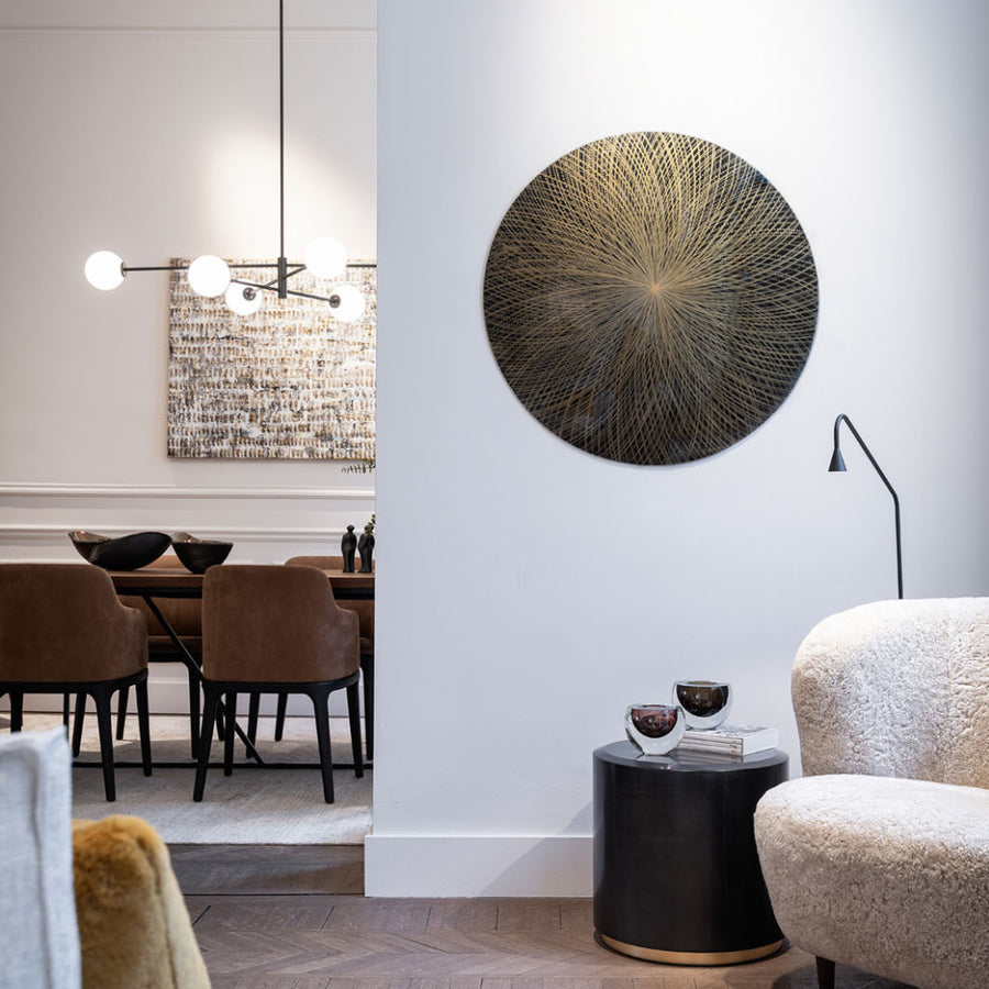 Modern living room with a round decorative wall piece, side table, and chairs.