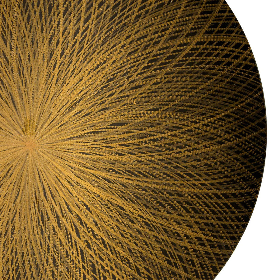 Close-up of a textured gold circular object with a starburst pattern on a black background