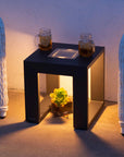 Black side table with a plant and two glasses on a patio with solar light by Les Jardins available at Spacio retail stores in Mumbai & Kolkata. 