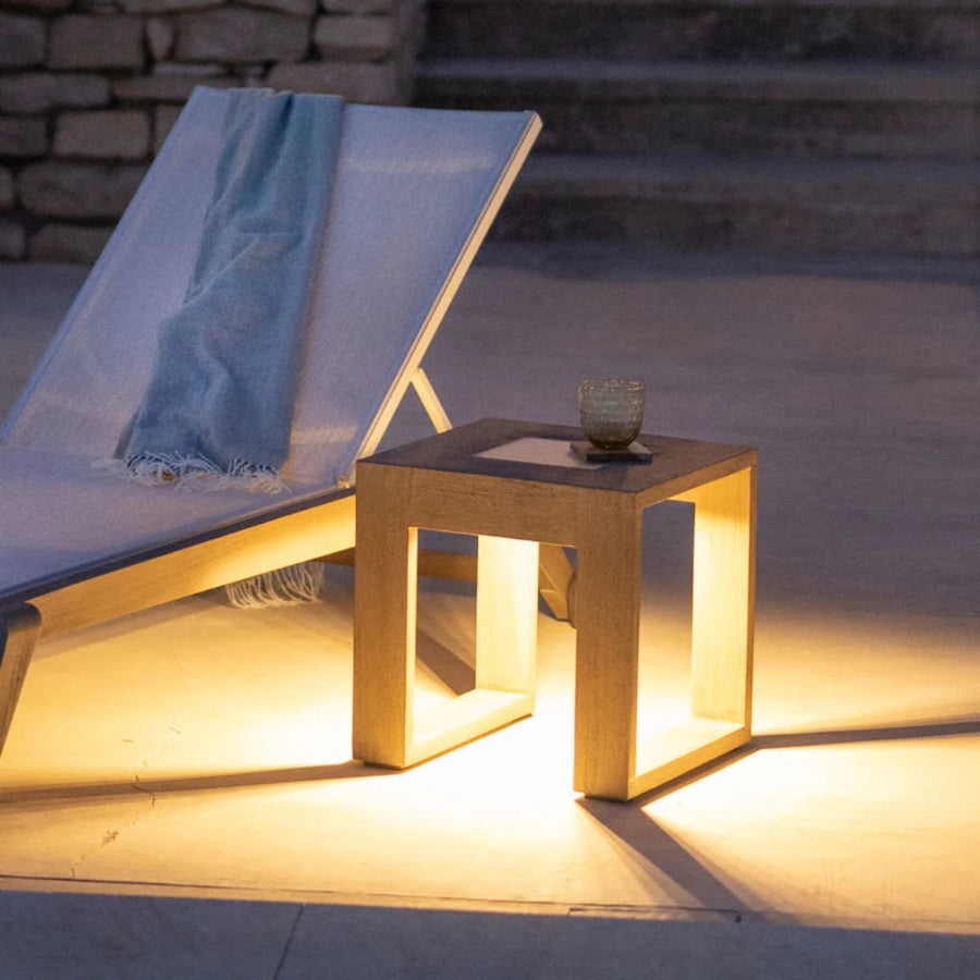 Outdoor setting with a lounge chair and small table illuminated by solar warm light  by Les Jardins available at Spacio retail stores in Mumbai & Kolkata. 