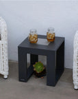 Black solar light side table with two jars of iced tea between two white wicker chairs against a light gray wall by Les Jardins available at Spacio retail stores in Mumbai & Kolkata. 