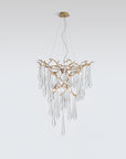 A Serip Aqua Chandelier from the Serip brand, crafted with gold and crystal materials, hangs elegantly from a white wall.