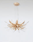 A flower shaped chandelier suspending from the ceiling on a light grey colour background. 