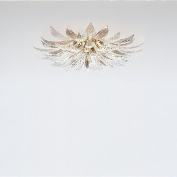 A flower shaped light with glass and metal fixed on the ceiling on a light grey colour background