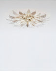 A flower shaped light with glass and metal fixed on the ceiling on a light grey colour background