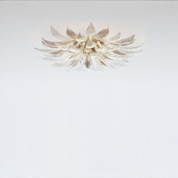 A flower shaped light with glass and metal fixed on the ceiling on a light grey colour background