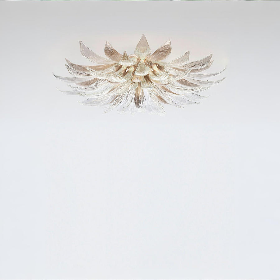 A flower shaped light with glass and metal fixed on the ceiling on a light grey colour background