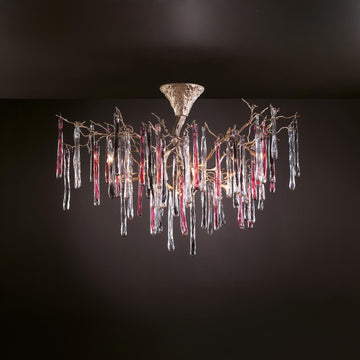 A colourful chandelier suspended from a ceiling with colourful glass icicles hanging from golden colour branches on a dark grey background.