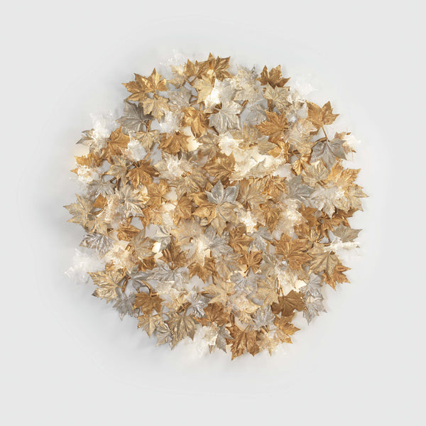 Decorative wall sculptural light with gold, silver, and bronze leaves on a light gray background from Serip's Folio collection, available at Spacio. 