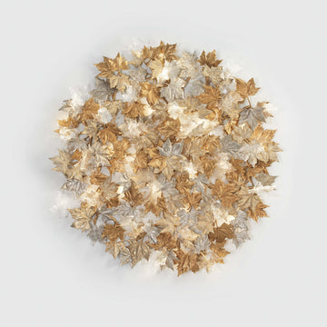 Decorative wall sculptural light with gold, silver, and bronze leaves on a light gray background from Serip's Folio collection, available at Spacio. 