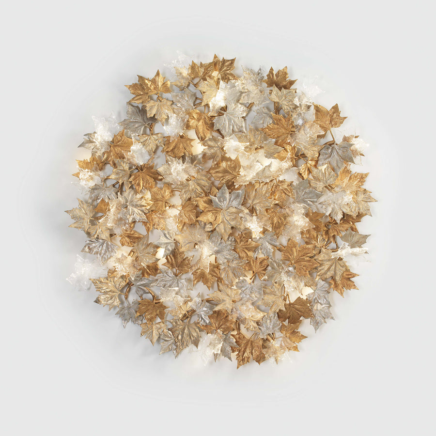 Decorative wall sculptural light with gold, silver, and bronze leaves on a light gray background from Serip's Folio collection, available at Spacio. 