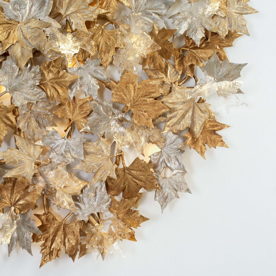 Close up of decorative sculptural wall lights with leaves in gold and silver on a white background