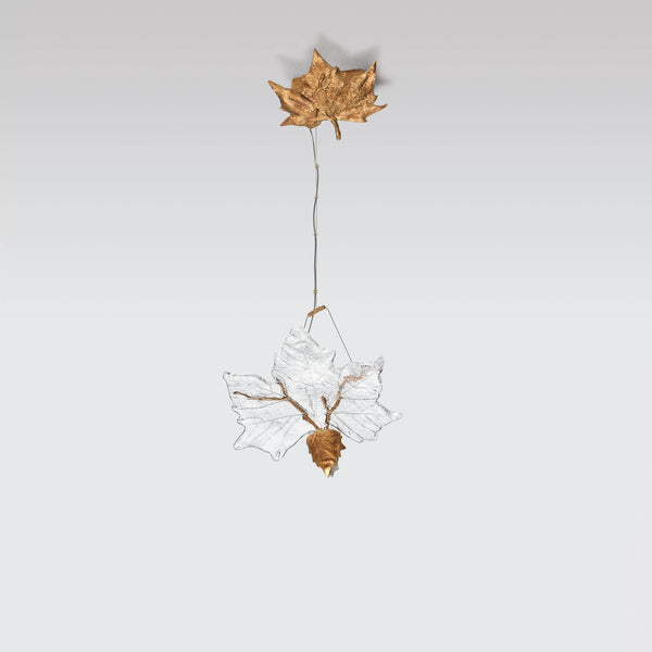 Decorative hanging light with a gold leaf and glass design on a light gray background