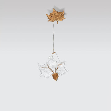 Decorative hanging light with a gold leaf and glass design on a light gray background