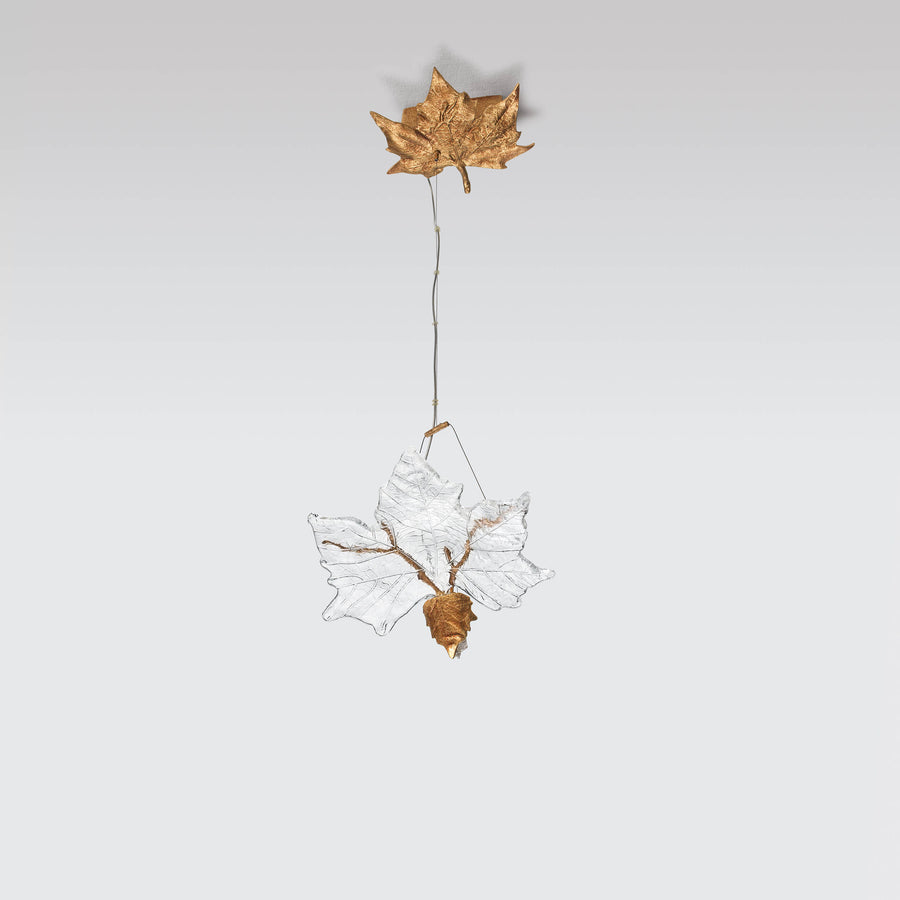 Decorative hanging light with a gold leaf and glass design on a light gray background