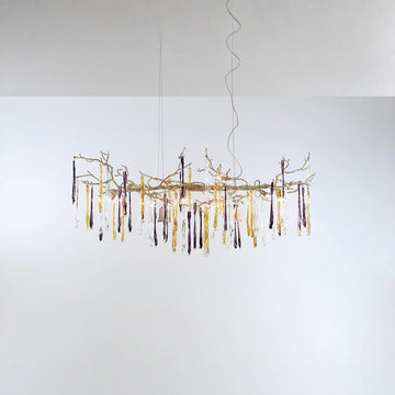 A chandelier hanging from the ceiling with colourful icicles shape glass on a light grey colour background