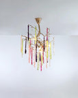 A colourful chandelier suspended from a ceiling with colourful glass icicles hanging from golden colour branches on a light grey background.