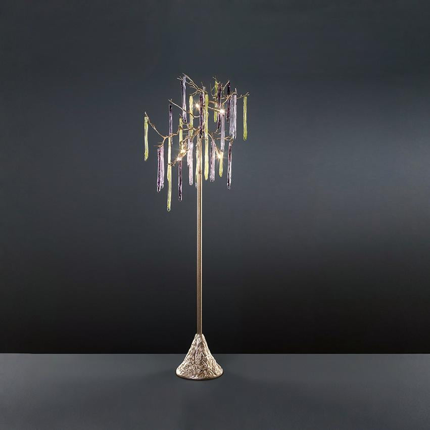 A floor lamp with colourful glass icicles hanging from metal branches on a grey background