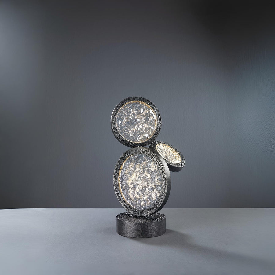Decorative black finish table lamp with circular design on a gray background