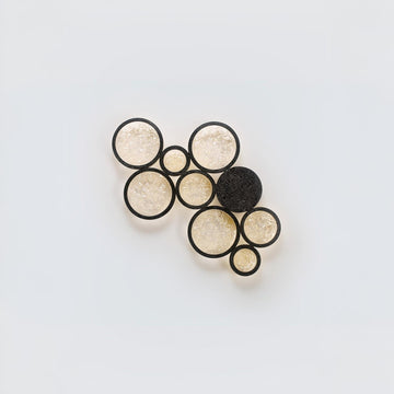 Set of black and gold circular earrings shaped wall light on a light gray background