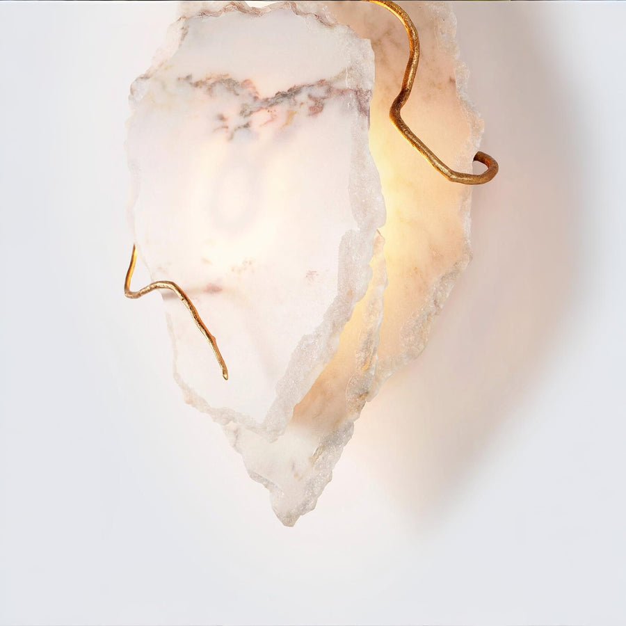 Decorative wall light fixture with marble finish and gold accents on a white background