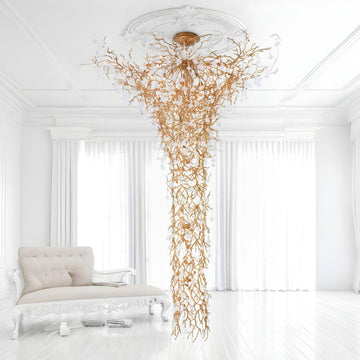 Luxurious chandelier hanging in a white room with a sofa.