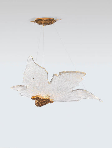 Decorative sculptural hanging light in leaf shape made of brass and glass with gold accents on a white background